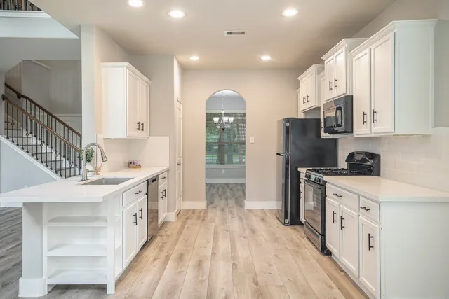 a kitchen with stainless steel appliances granite countertop a lot of cabinets and wooden floors
