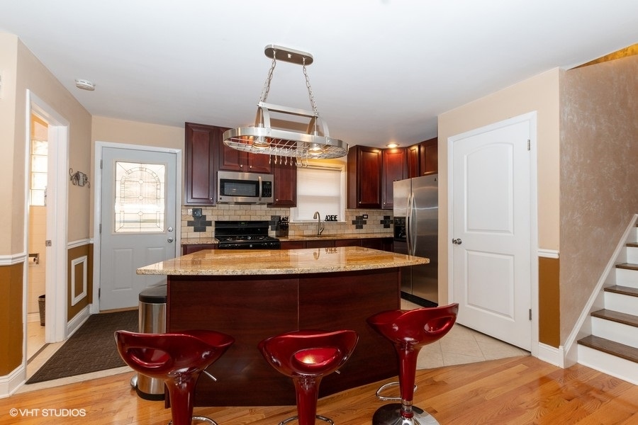 2605 West 83rd Place Chicago, IL 60652 - Photo 5 of 14 a kitchen with stainless steel appliances granite countertop a stove refrigerator and a dining table with wooden floor