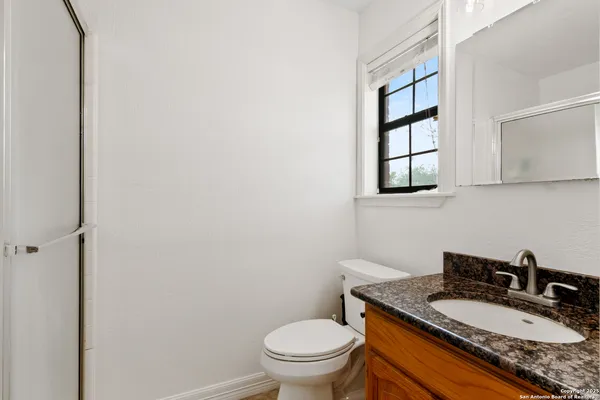 a bathroom with a granite countertop toilet a sink and a mirror