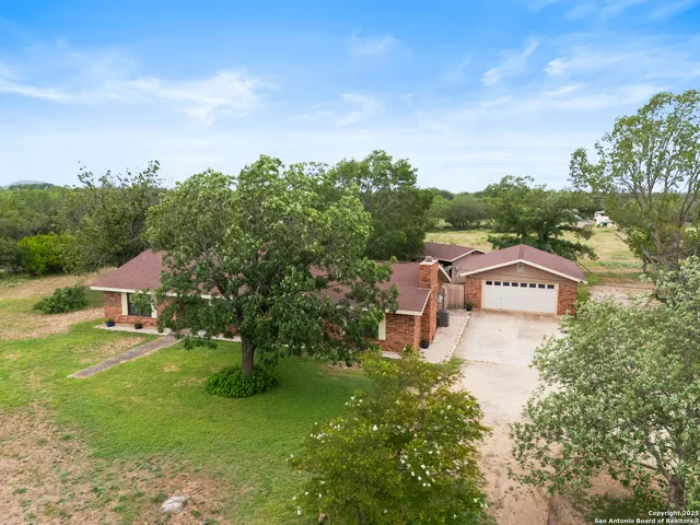 an aerial view of a house with garden space and trees all around