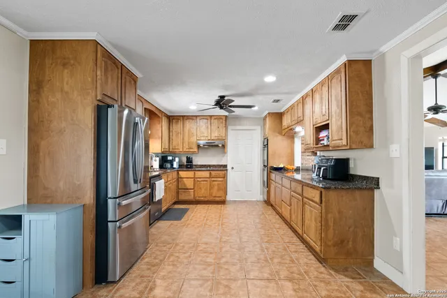 a kitchen with granite countertop a refrigerator stove top oven and sink