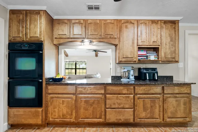 a kitchen with kitchen island granite countertop a stove a sink and a microwave