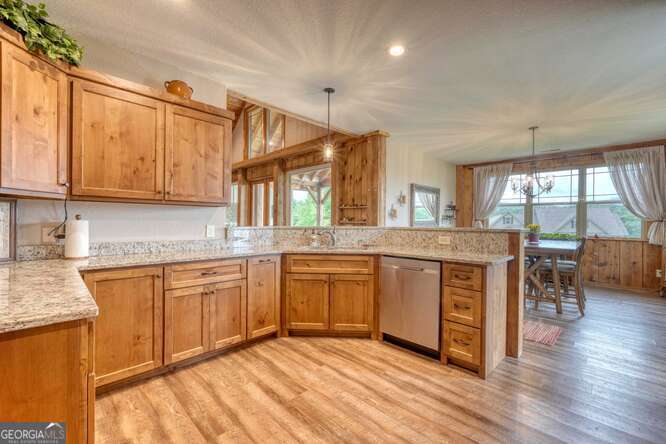 85 Minstead Ridge Young Harris, GA 30582 - Photo 26 of 50 a kitchen with stainless steel appliances granite countertop wooden cabinets a sink a stove a dining table and chairs