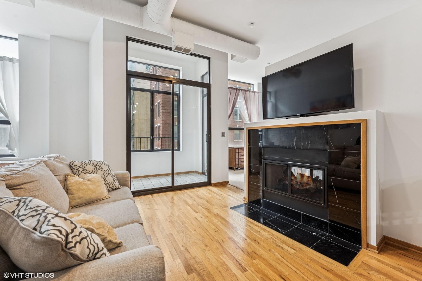 910 South Michigan Avenue, Unit 710 Chicago, IL 60605 - Photo 2 of 17 a living room with furniture a flat screen tv and a fireplace