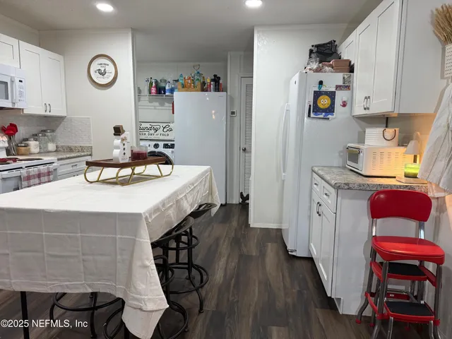 a kitchen with stainless steel appliances a white refrigerator a stove a sink and a dining table with wooden floor