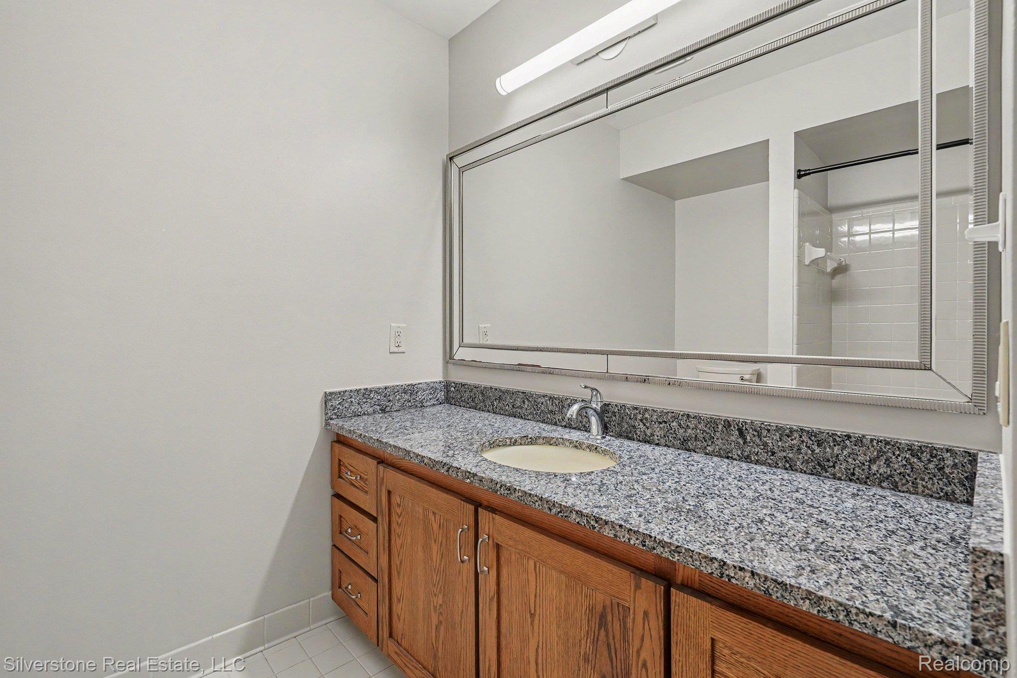 1502 Meadowside Drive Rochester, MI 48307 - Photo 21 of 27 Bathroom vanity featuring a granite countertop, undermount sink, and wood cabinetry