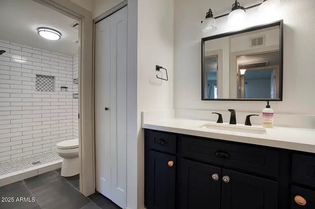 a bathroom with a toilet sink double vanity and mirror