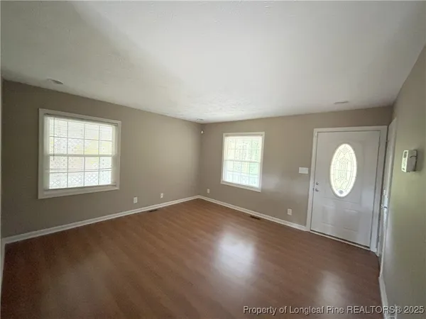 an empty room with wooden floor and windows