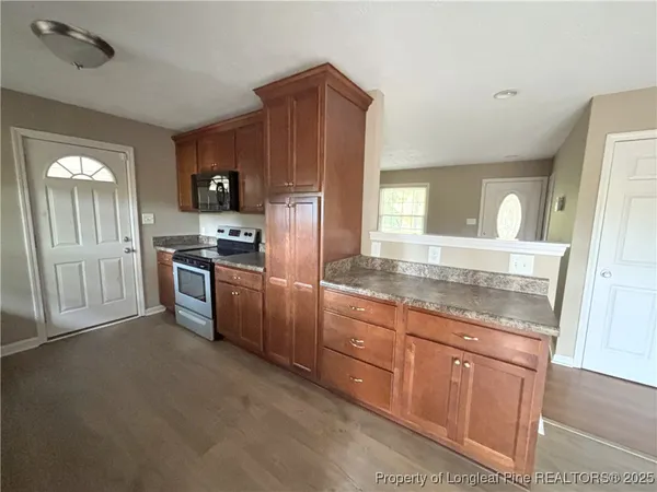 a kitchen with granite countertop stainless steel appliances a stove top oven and refrigerator