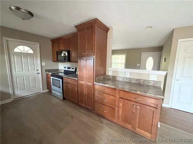 a kitchen with granite countertop stainless steel appliances a stove top oven and refrigerator