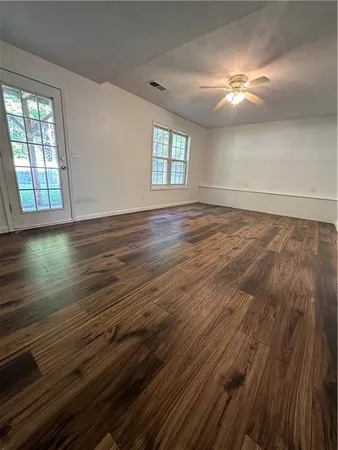 an empty room with wooden floor and windows