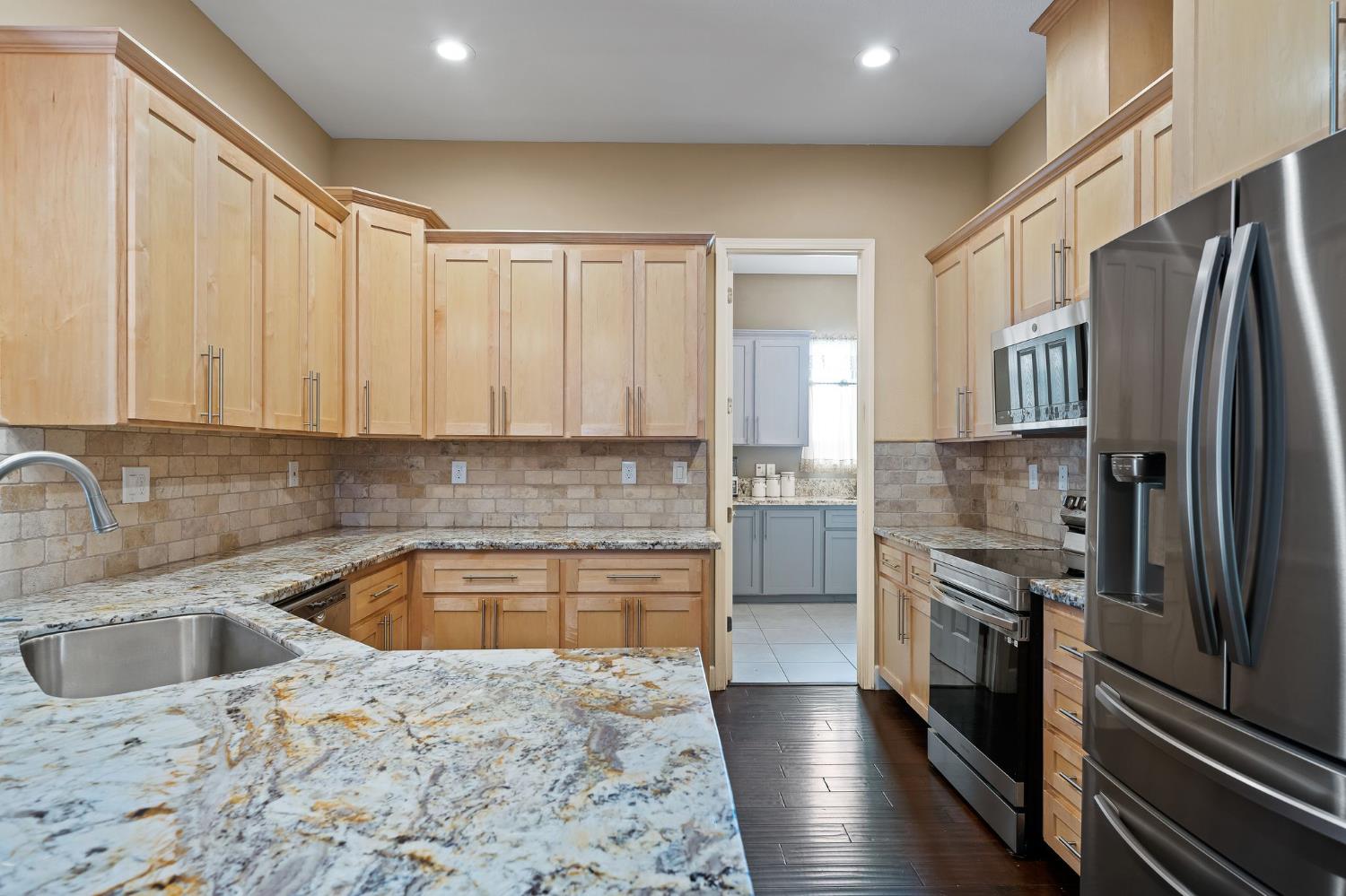 209 Fall Avenue Patterson, CA 95363 - Photo 13 of 48 a kitchen with stainless steel appliances granite countertop a refrigerator a sink a stove and island