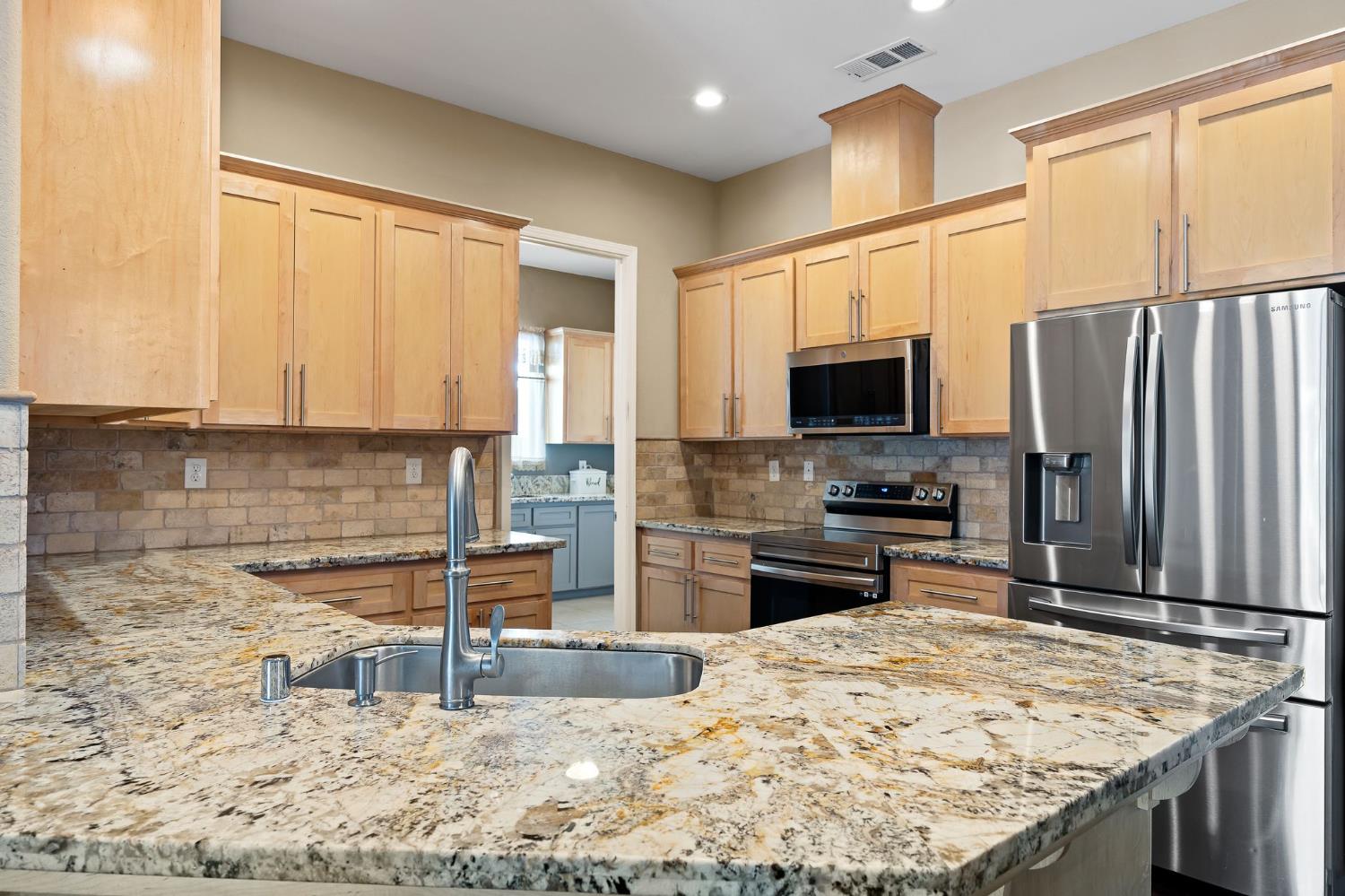 209 Fall Avenue Patterson, CA 95363 - Photo 14 of 48 a kitchen with kitchen island granite countertop a stove sink microwave and refrigerator