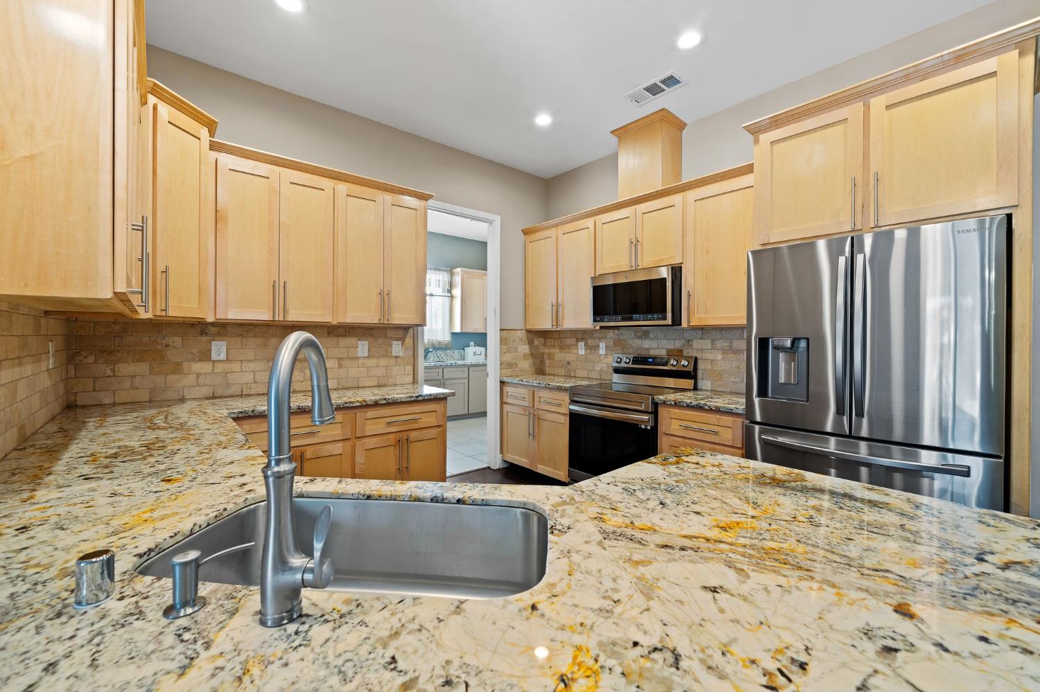 209 Fall Avenue Patterson, CA 95363 - Photo 15 of 48 a kitchen with granite countertop a refrigerator and a stove top oven