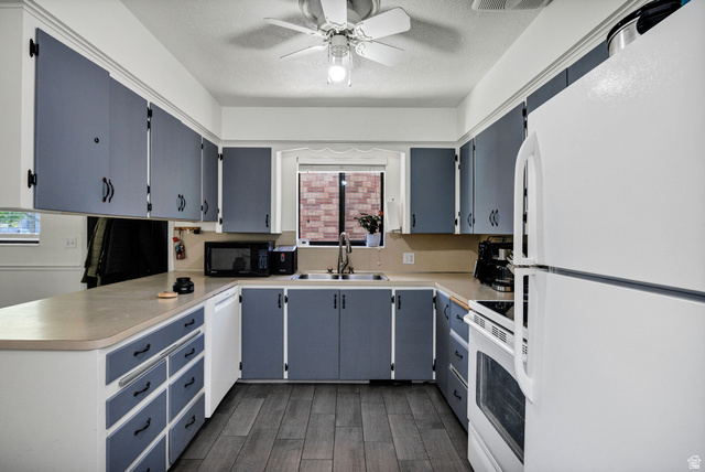 667 North 100 East Logan, UT 84321 - Photo 16 of 41 Kitchen with white appliances, light countertops, gray cabinetry, a textured ceiling, and a peninsula