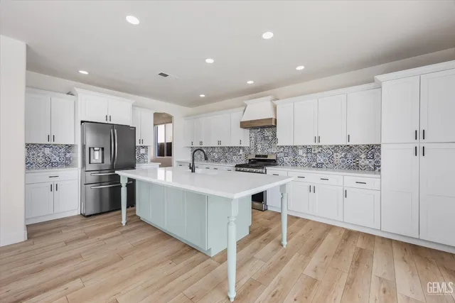 a kitchen with stainless steel appliances white cabinets a sink and a stove