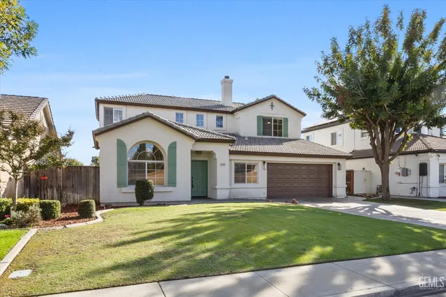 a view of a white house with a large yard and large tree