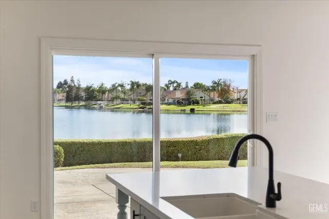 a view of an empty room with kitchen and window