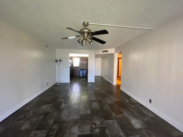 a view of n empty room with a ceiling fan and window