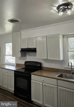 a kitchen with granite countertop a sink a stove and cabinets