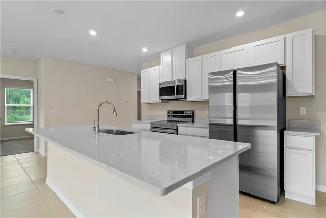 a kitchen with stainless steel appliances granite countertop a sink a refrigerator and a microwave