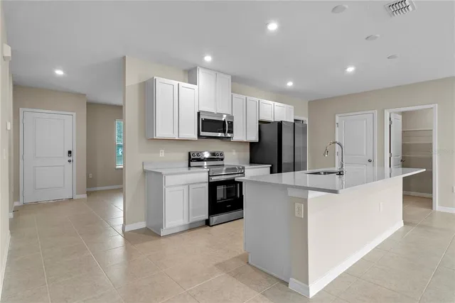 a kitchen with kitchen island a white counter top space stainless steel appliances and cabinets
