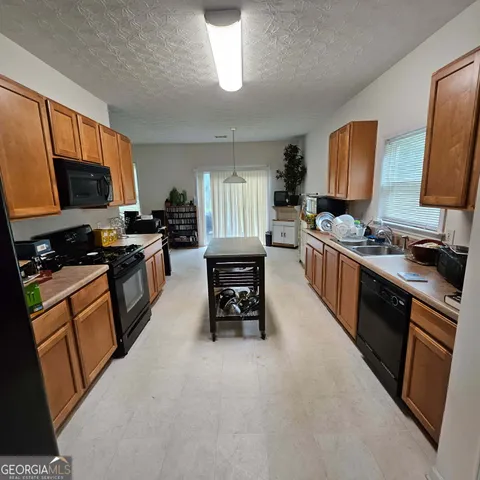 a kitchen with stainless steel appliances granite countertop a stove top oven a sink dishwasher and wooden cabinets