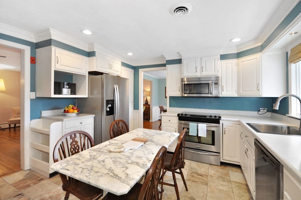51 Melvin Road Arlington, MA 02474 - Photo 27 of 42 a kitchen with stainless steel appliances granite countertop a table chairs sink refrigerator and microwave
