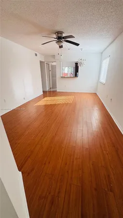 an empty room with wooden floor fan and windows