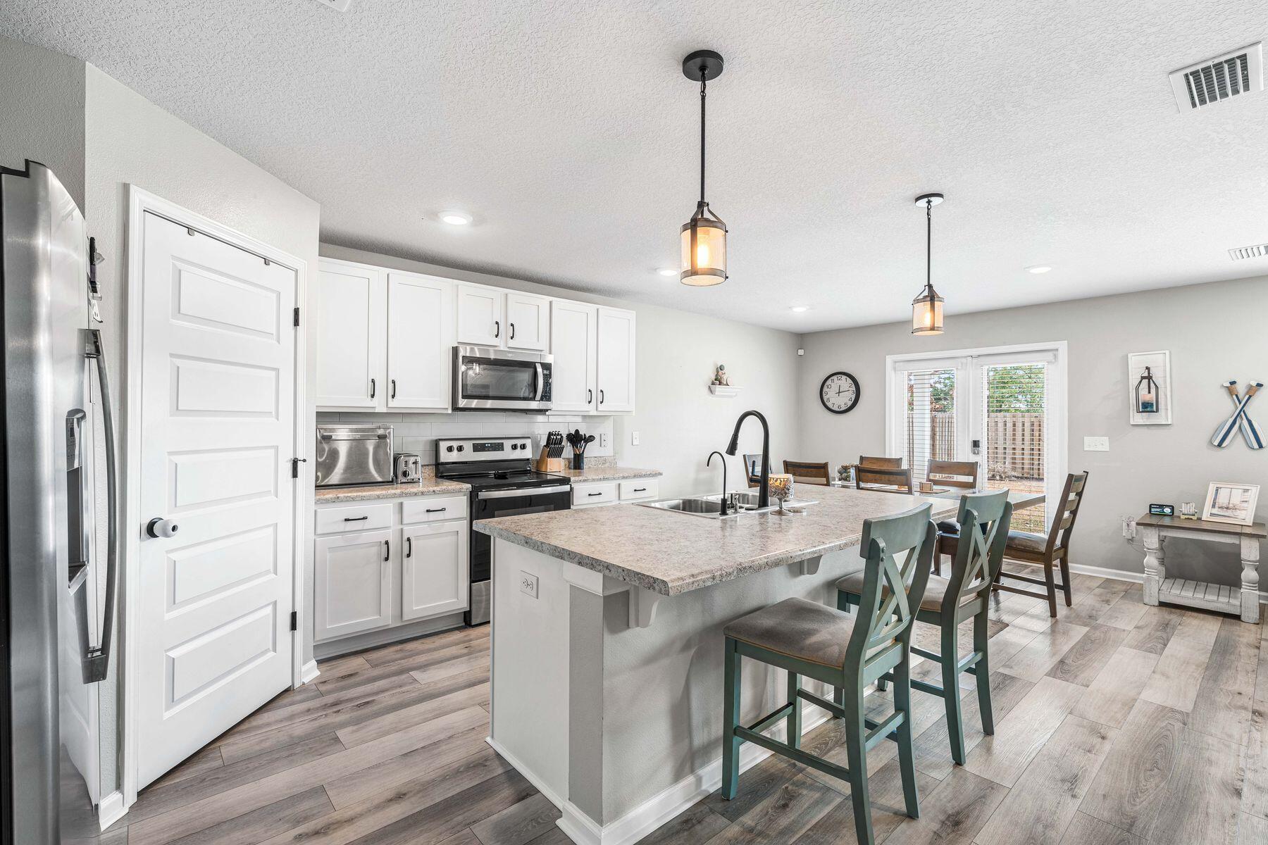396 This Way Freeport, FL 32439 - Photo 6 of 30 a kitchen with stainless steel appliances granite countertop a stove top oven a sink dishwasher a dining table and chairs with wooden floor
