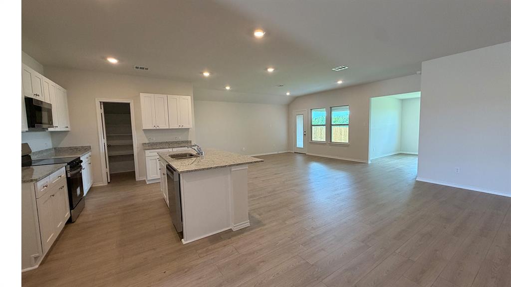 2003 Reveille Way Terrell, TX 75160 - Photo 15 of 25 Open-concept living area featuring wood-finish flooring, recessed lighting, and a kitchen with white cabinetry
