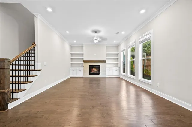 an empty room with wooden floor fireplace and windows