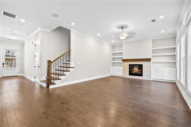 an empty room with wooden floor fireplace and windows