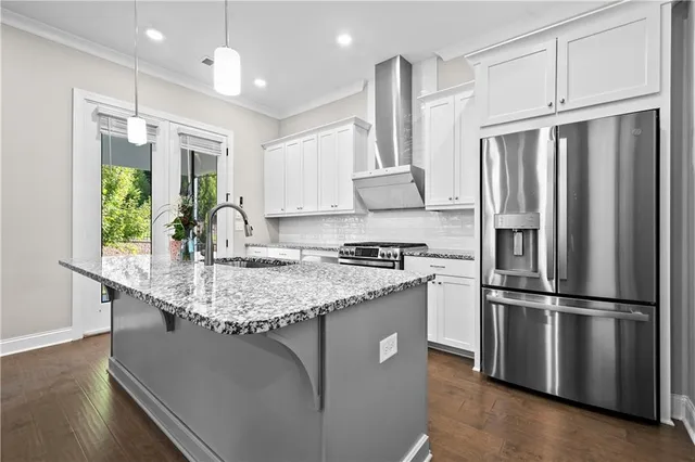 a kitchen with stainless steel appliances granite countertop a refrigerator a sink dishwasher a stove and a refrigerator with wooden floor