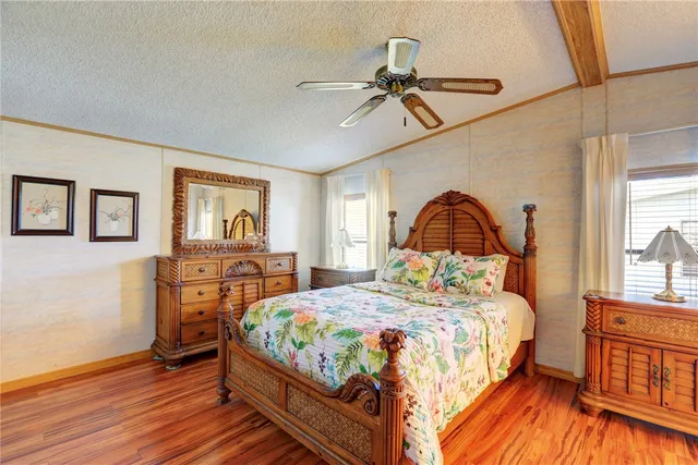 a bedroom with a bed a dresser and wooden floor
