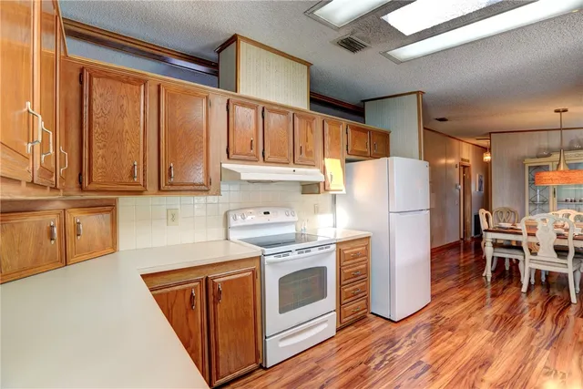 a kitchen with a refrigerator a stove and wooden floors