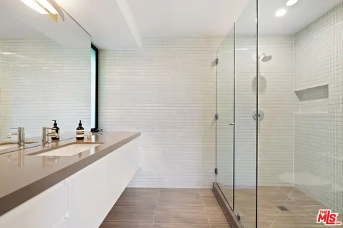 a bathroom with a double vanity sink a mirror and shower