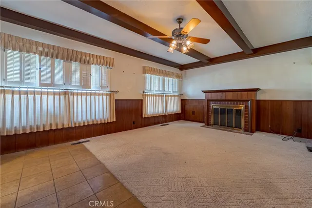 a view of an empty room with chandelier fan and windows