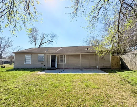 a view of a house with a yard and large trees