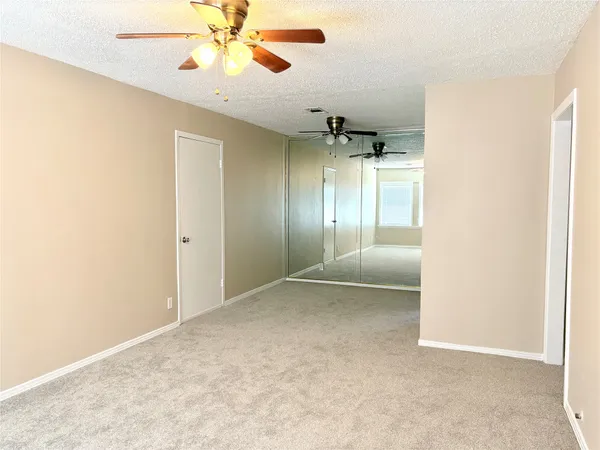 an empty room with a ceiling fan and glass door