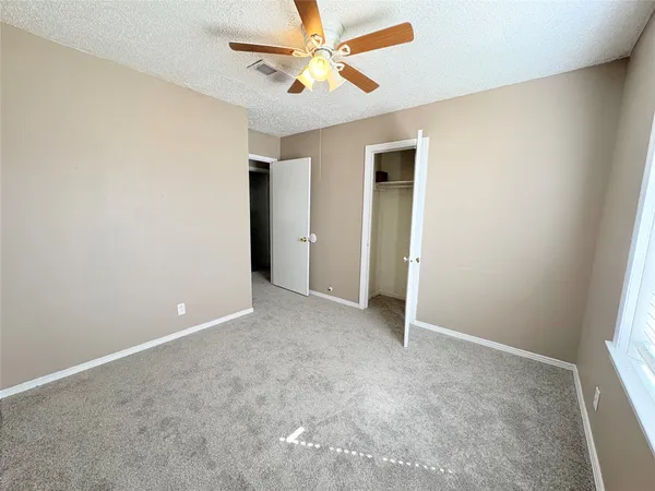an empty room with closet and a ceiling fan
