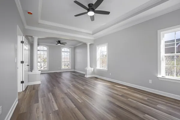an empty room with wooden floor and windows