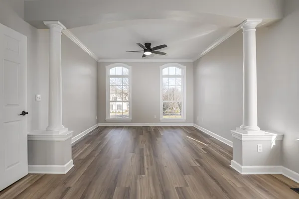 a view of an empty room with window and wooden floor