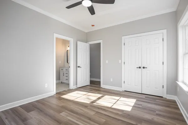 a view of empty room with wooden floor and fan