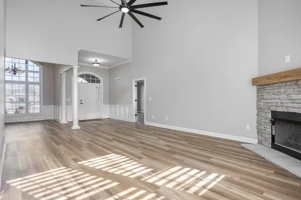 an empty room with wooden floor fan and windows