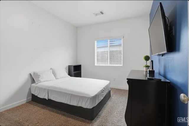 a bedroom with a bed tv on table and a window