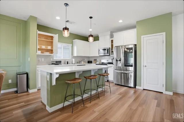 a kitchen with a refrigerator a sink dishwasher a stove and a microwave oven with wooden floor