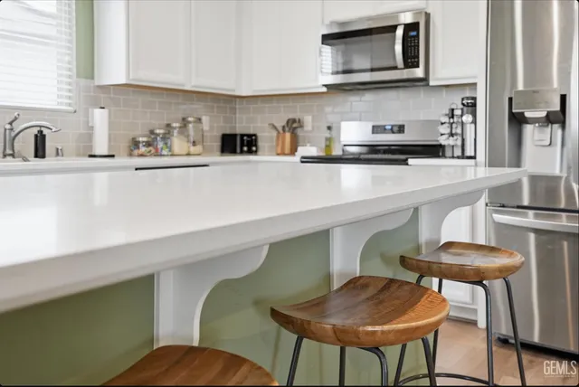 a kitchen with stainless steel appliances a white table chairs in it