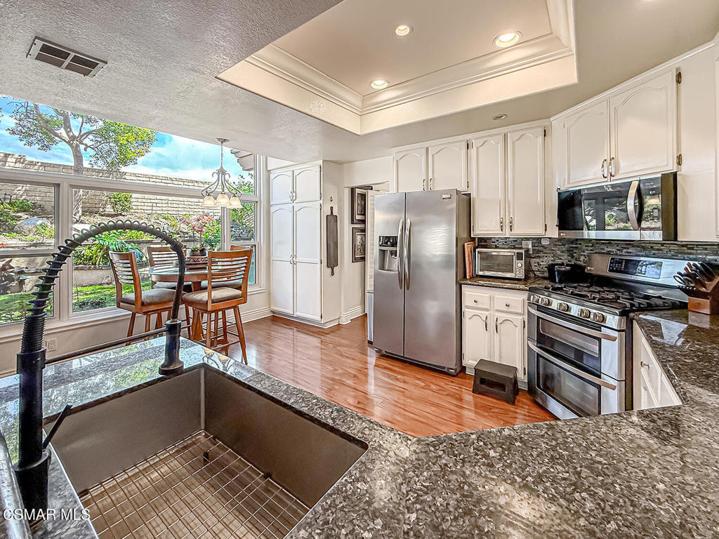 7204 University Drive Moorpark, CA 93021 - Photo 17 of 57 a kitchen with stainless steel appliances granite countertop a stove a refrigerator a sink a dining table and chairs with the wooden floor