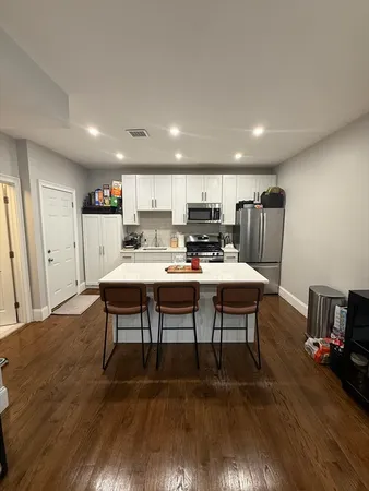 a living room with stainless steel appliances furniture and wooden floor